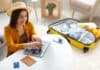 Happy young woman planning vacation travel with laptop, source: Shutterstock