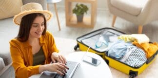 Happy young woman planning vacation travel with laptop, source: Shutterstock