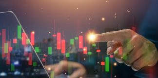 Hand at stockmarket chart, source: Shutterstock