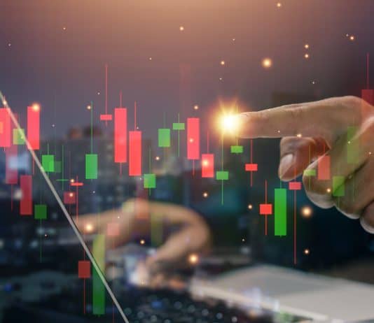 Hand at stockmarket chart, source: Shutterstock